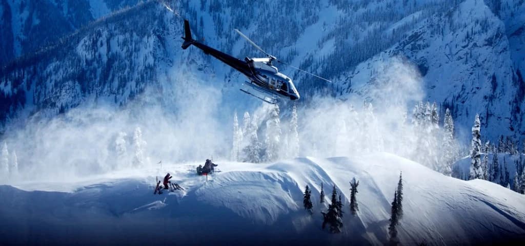 Helikopter im Schwebeflug über einem verschneiten Grat mit Skifahrern und Rotorabwind