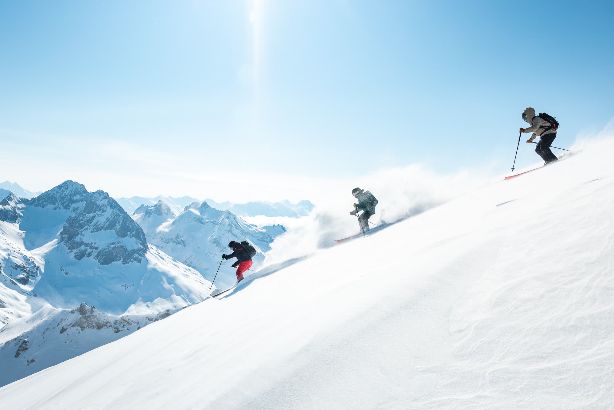 Tres esquiadores bajando powder en una cresta alpina